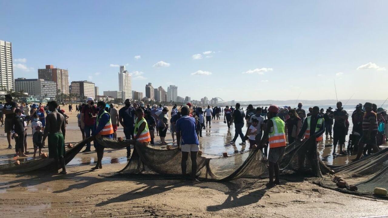 26 June 2021, South Africa, Durban: Trawl fishermen who have brought their sardine catch to the beach pack up their nets. Sardine dishes of all kinds are currently on the menu in the coastal region around South Africa’s port city of Durban. The reason is a natural spectacle that triggers a mass rush onto the beaches every year: the « Sardine Run », triggered by the cold winter temperatures in the southern hemisphere. Photo: Ralf Krüger/dpa (Photo by Ralf Krüger/picture alliance via Getty Images)