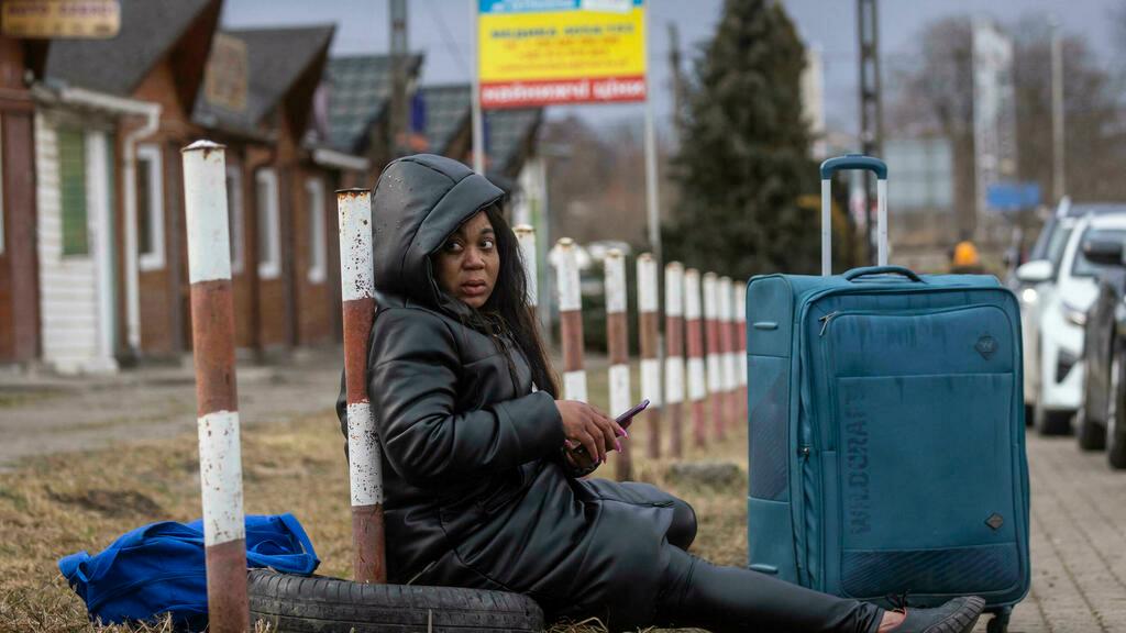 An African woman is seen resting at the Medyka pedestrian border in eastern Poland on February 27, 2022. – As Ukraine braces for a feared Russian invasion, its EU member neighbours are making preparations for a possible influx of hundreds of thousands or even millions of refugees fleeing military action. (Photo by Wojtek RADWANSKI / AFP)
