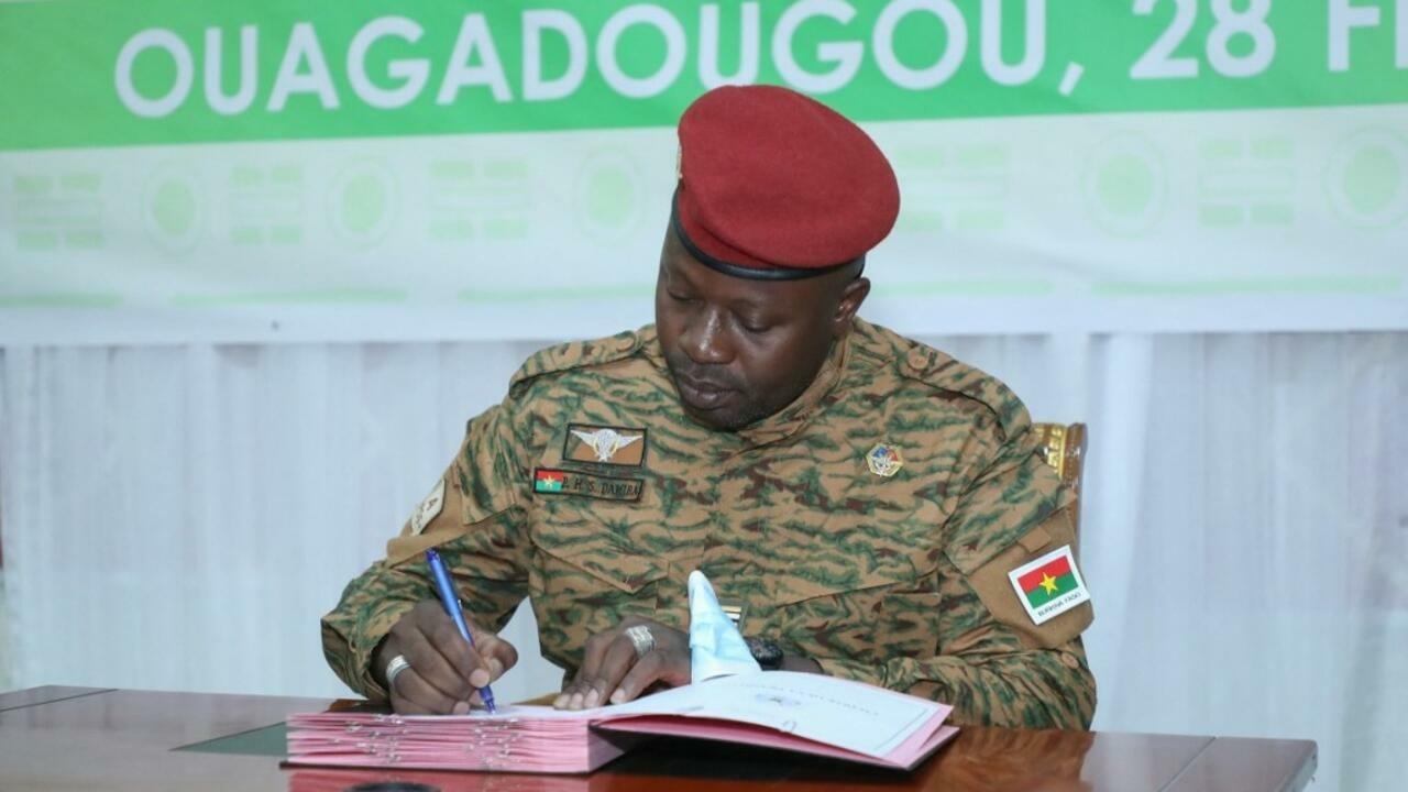 This handout picture released by the press office of Burkina Faso’s president shows the head of the junta Lieutenant Colonel Paul-Henri Sandaogo Damiba, signing a charter setting a three-year transition period before the country holds elections, in Ouagadougou on March 1, 2022. – The transition period before a return to constitutional order in Burkina Faso, where a coup took place on January 24, was set at three year by national meetings which brought together the « living forces » of the country. (Photo by Leonard BAZIE / Burkina Faso Presidency / AFP) / RESTRICTED TO EDITORIAL USE – MANDATORY CREDIT « AFP PHOTO / Press office of Burkina Faso’s president/ Leonard BAZIE – NO MARKETING NO ADVERTISING CAMPAIGNS – DISTRIBUTED AS A SERVICE TO CLIENTS