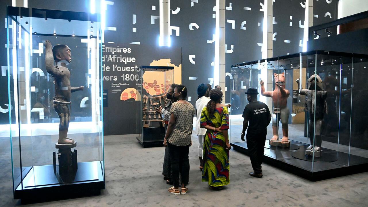 Visitors stand to view artefacts looted by French colonial soldiers returned and displayed for viewing by the general public during an exhibition at the presidency in Benin’s capital Cotonou, on February 20, 2022. – Twenty-six artefacts looted by French colonial soldiers from the Abomey Kingdom in 1892 returned and presently being exhibited has been opened for viewing by the general public at the presidency in Benins capital Cotonou. (Photo by PIUS UTOMI EKPEI / AFP)