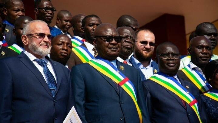 Central African National Assembly President Simplice Mathieu Sarandji (C) and the representative of Russian instructors deployed in the Central African Republic Alexandre Ivanov (L) and First Vice President of the National Assembly Evariste Ngamana (R) pose for a photograph on the steps of the National Assembly in Bangui on October 15, 2021. – Russian paramilitaries received a standing ovation from the Central African National Assembly for their « great efficiency » in « recapturing » rebel-held areas on October 15, 2021 just before Central African Republic President Touadéra announced a nationwide cease-fire. (Photo by AFP)