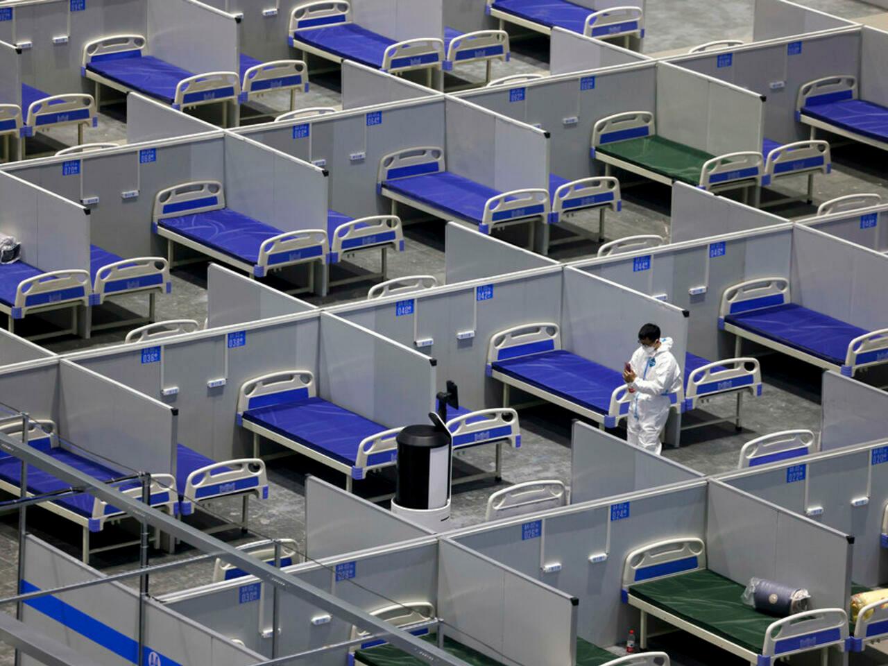In this photo released by Xinhua News Agency, a staff member adjusts a robot at the construction site of a temporary hospital at the National Exhibition and Convention Center (Shanghai) in east China’s Shanghai, Friday, April 8, 2022. China’s largest city of Shanghai will soon begin lifting lockdown in communities that report no positive cases within 14 days after another round of COVID-19 testing, authorities said Saturday. (Jin Liwang/Xinhua via AP)