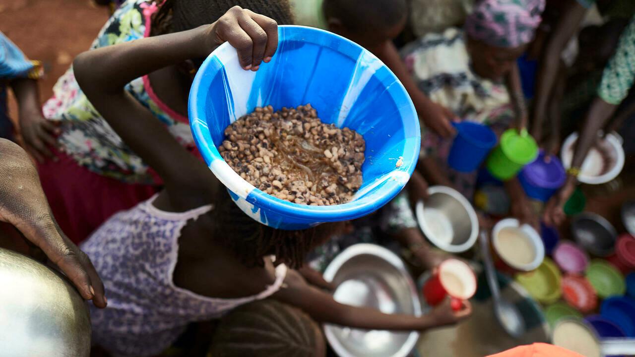 A Fulani girl woman holds a bowl of food on her head in an Internally Displaced People’s (IDP) camp in Faladie, where nearly 800 IDPs have found refuge after fleeing inter-communal violence in central Mali, on May 14, 2019. – Built up on a landfill, this camp bears critical hygienic conditions for the displaced people who live surrounded by rubbish. (Photo by MICHELE CATTANI / AFP)